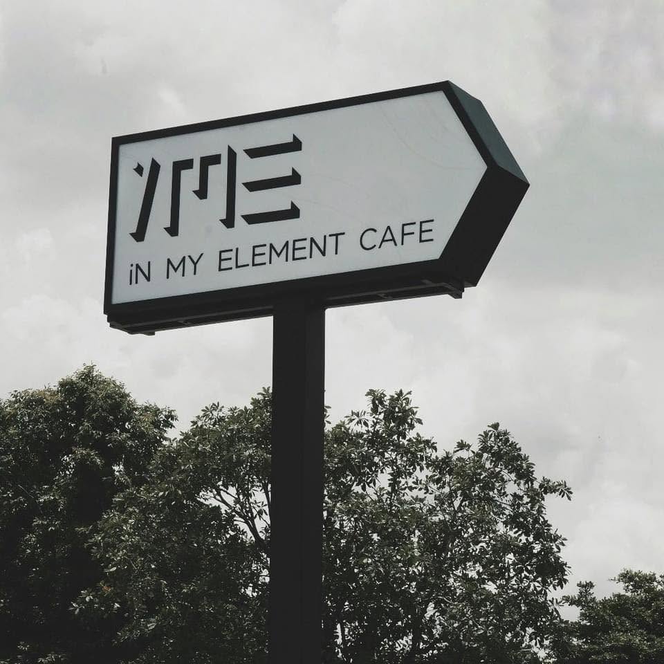 Daylight falling through the glass roof onto the raw concrete interior and central tree at In My Element Cafe.